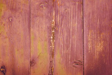 Scratched paint in rose hues on an old wooden door
