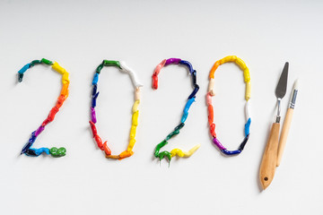 The number 2020 are painted on white canvas with bright oil paints. Top view close up.