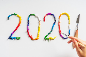 The number 2020 are painted on white canvas with bright oil paints. Top view close up.