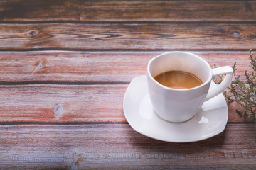 Hot coffee in a white glass on the old wooden floor on the side with flowers ,copy the area for the text