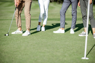 People practising golf, scoring the ball with putter into the hole on the playing course, close-up view with no face