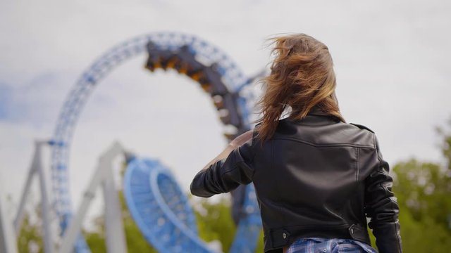 Young girl waves to her friends while they ride on a roller coaster
