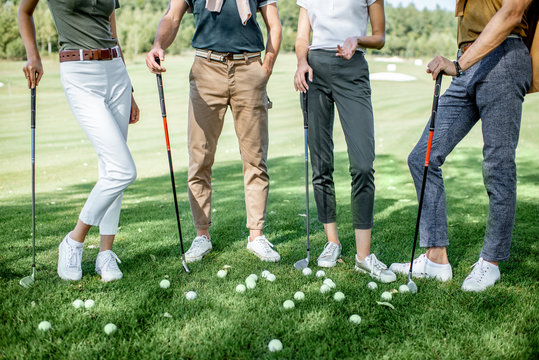 Friends standing together with golf equipment and balls on the green grass, cropped image with no face