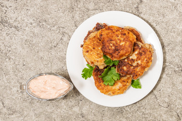 Fritters decorated with greens on a white plate. View from above.