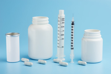 Syringes and white bottles with pills on a blue background.