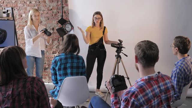 photography workshop, a group of young people with digital cameras in their hands study the lens and camera device in a professional photo studio