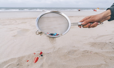 Young woman cleaning microplastics from sand on the beach, Environmental problem, pollution, ecolosystem and climate change warning concept 