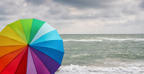 Colorful of umbrella on the beach and foam of sea waves at a thunderstorm, Weather concept image