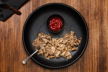 Pulled pork sobre plato negro redondo vista desde arriba