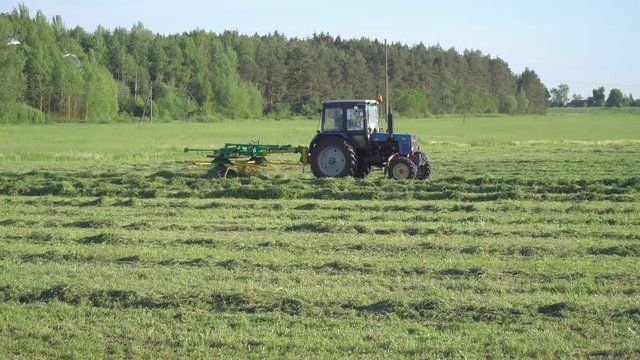 tractor raking hay in a field