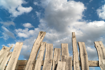 old wooden gray natural planks on a background of blue sky and white clouds