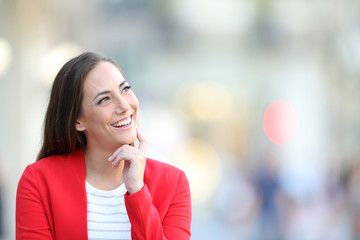 Fototapeta premium Happy woman in red thinking looking at side outdoors
