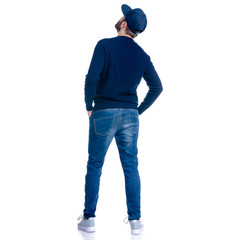 Man in jeans shorts, cap, casual clothing standing looking up on white background isolation, rear...