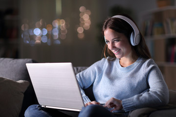 Happy girl watching and listening videos on laptop