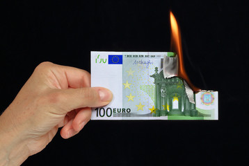 hand holding a burning european currency bank note