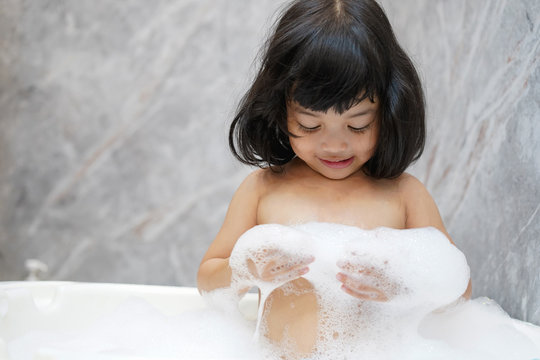 Asian baby kid bathing concept. adorable girl in bathtub with fluffy soap bubble.