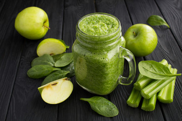 Green smoothies with spinach, apple and celery  on the black wooden background