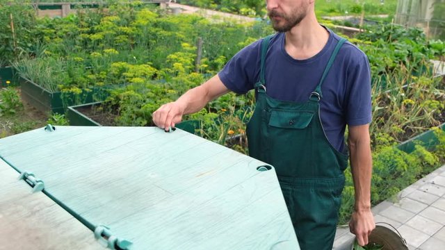 Farmer throws weeds and organic waste from his garden into compost heap. Composting - eco friendly recycling technology.