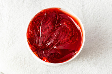 Red transparent sugaring paste in a white jar