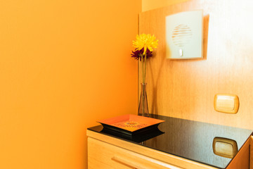 detail of bedroom bedside table with vase with flowers and light on the wall