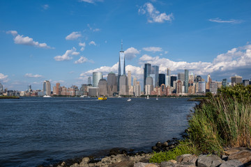 Obraz premium Lower Manhattan skyline with boat and ferry on Hudson river view from Liberty State Park in late summer