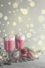 Obraz na płótnie Canvas Pink hot chocolate winter drink with whipped cream and marshmallows. Macaroons and christmas lights. Copy Space