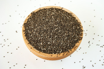 Chia seeds in a wood bowl on white background