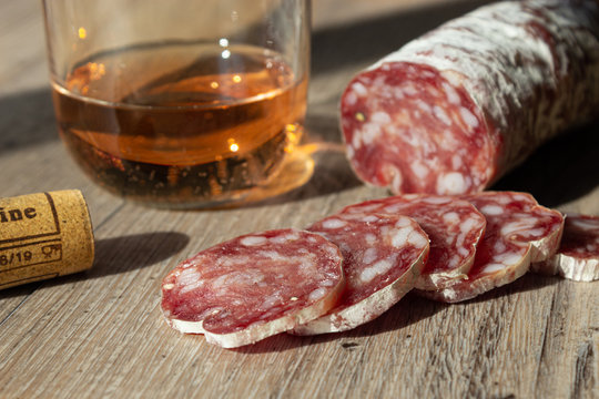 fette di salame bicchiere di vino e tappo di sughero su fondo legno