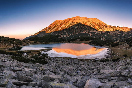 Pirin mountain national park. Panoramic colorful sunset view of Todorka peak with reflection in Muratovo lake, Bulgaria