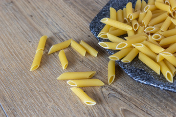 pasta penne non cotte su fondo legno