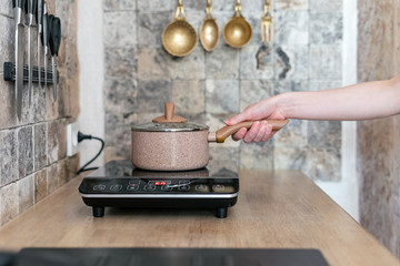 Girl cooking food in kitchen with small electric stove