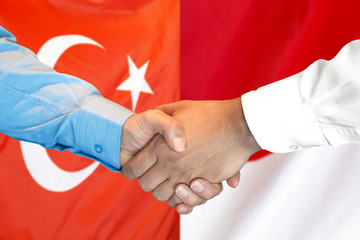 Handshake on Turkey and Monaco flag background.