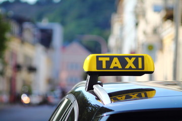 A yellow taxi sign on car in german city. Car roof. Selective focused image.
