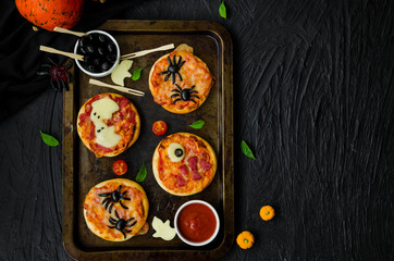 Halloween Mini Pizza Monsters on a black background. Spider Pizza, Ghost Pizza, Monster Pizza.  Food idea for Halloween party.