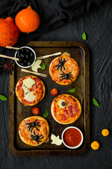 Halloween Mini Pizza Monsters on a black background. Spider Pizza, Ghost Pizza, Monster Pizza.  Food idea for Halloween party.
