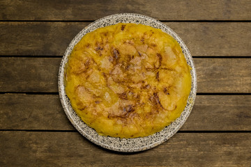 vegan Spanish omelette with potatoes onion and garlic, isolated in a wooden table