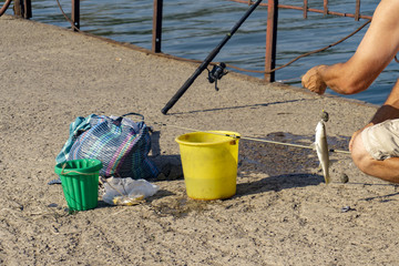 The fisherman caught the fish and removes it from the hook.