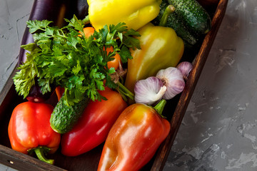 Autumn vegetables (bell peppers, eggplant, cucumbers) in a wooden box on a wooden table. The concept of healthy and diet food.