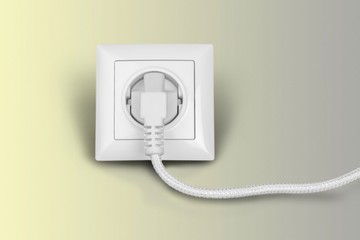 White electrical plug in the electric socket on a wall