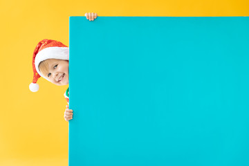 Happy child holding blue Christmas banner blank against yellow background