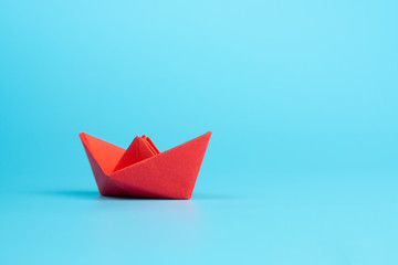 Origami red paper boat on blue background