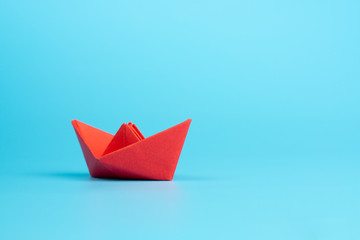 Obraz premium Origami red paper boat on blue background