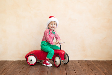 Happy child wearing Santa Claus costume playing at home