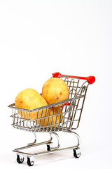 Conceptual image of a miniature shopping trolley filled with potatoes isolated on a white background with space for copy