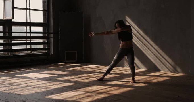 Contemporary dance. Girl dancing on wood floor in the loft hall with beautiful light and shadows. Enjoying modern dance movement. Freestyle. Hobby and lifestyle
