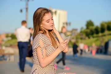 Beautiful girl in a light dress talking on the phone