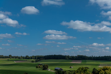 Fototapeta na wymiar Bayerischer Himmel mit leichten weißen Wolken vor blauem Himmel grünen Feldern und Wald gesehen von Andechs