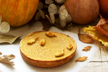 Naklejka na ściany i meble Traditional American pumpkin homemade cake, decorated with cookies on a background of pumpkins and autumn leaves.