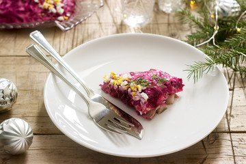 Traditional Soviet festive salad of herring and vegetables, served with vodka in a New Year's decoration. Rustic style.