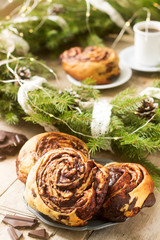 Obraz na płótnie Canvas Snail chocolate muffins served with coffee on the background of a wreath of fir branches and cones. Rustic style.